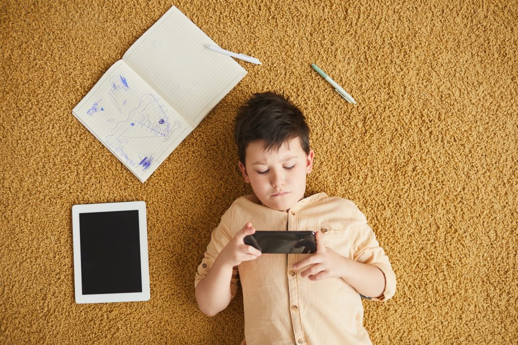 Modern Child Using Gadgets on Floor
