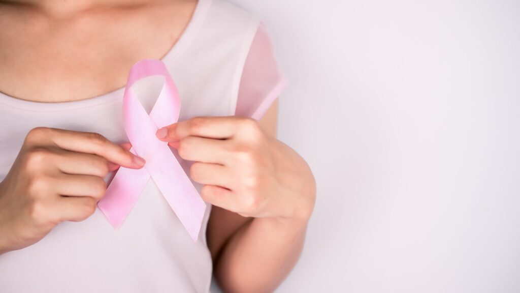 Woman wearing a white t-shirt is hand holding pink ribbon with white background, Breast cancer symbo