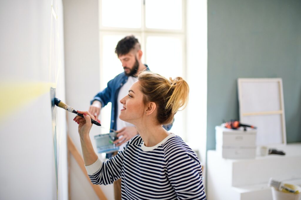 Mid adults couple painting wall indoors at home, relocation and diy concept.