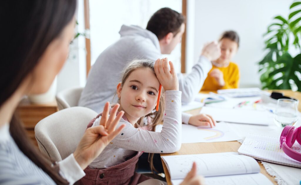 Parents with school girls indoors at home, distance learning.