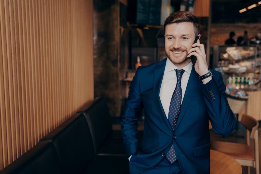 Well groomed bearded skilled banker in blazer suit talking on cellphone